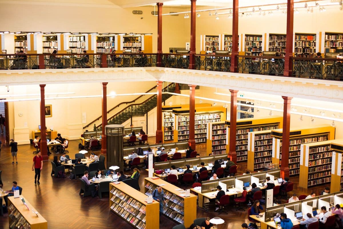 A busy library scene captures visitors studying and reading in a historic Melbourne building.